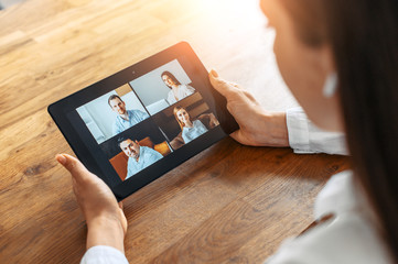 Wall Mural - Video meeting. A woman in formal white shirt is using a digital tablet for video connection, video call in the office. Online conference with several people together