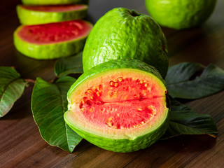 Fresh red guavas with green leaves on wooden demolition background. Wood texture and guava leaves.