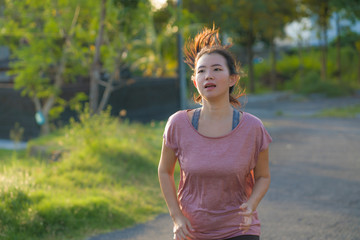 Wall Mural - outdoors running - young happy and dedicated Asian Korean woman jogging workout at beautiful city park or countryside trail on sunset enjoying fitness and cardio activity