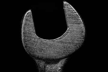 Macro detail of the head of a metal spanner on black background