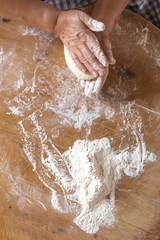 Female hands kneading dough on wooden table