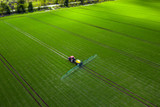 Fototapeta  - Agricultural industry, tractor spraying herbicides in green field