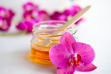 depilation and beauty concept - sugar paste or wax honey for hair removing with wooden waxing spatula sticks on flower background