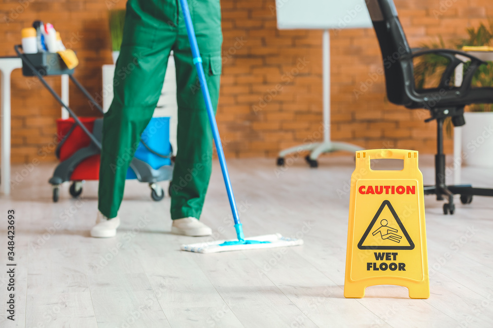 Male janitor mopping floor in office