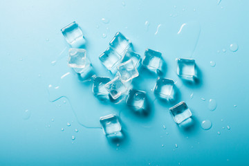 Wall Mural - Ice cubes with water on a blue background. Ice concept for drinks. Banner. Flat lay, top view