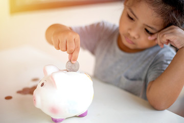 Kid putting coins into piggy bank