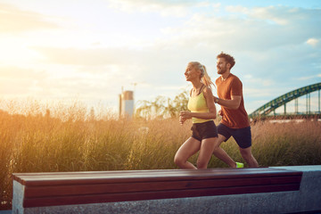 Modern woman and man jogging / exercising in urban surroundings near the river.