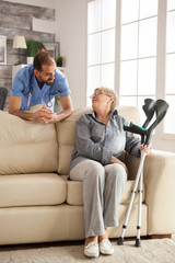 Young doctor with stethoscope in nursing home talking with senior woman.