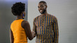 © JonoErasmus - Two smiling young African businesspeople shaking hands in an off