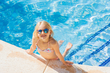 Summertime fun. Pretty little girl swimming in outdoor pool