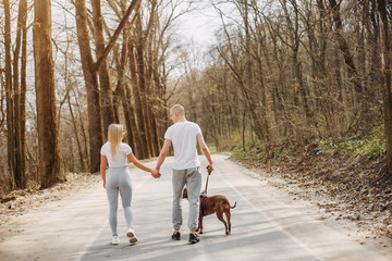 Beautiful couple in a park. Sportsman in a sportswear. Couple with a dog