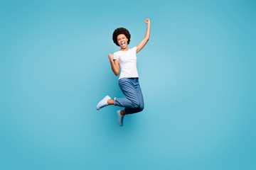 Canvas Print - Full length photo of ecstatic dark skin wavy lady jumping high sporty competitive person celebrating goal match fan wear casual white t-shirt jeans isolated blue color background