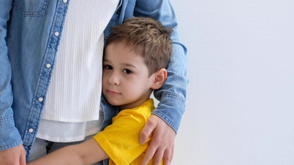 Sad little child, boy, hugging his mother at home, copy space. Family concept