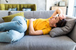 © F8  \ Suport Ukraine - Young woman with stomach ache lying on a sofa