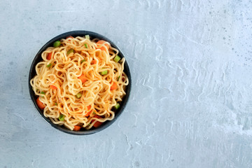 Wall Mural - Instant noodles with carrot, scallions, and a sauce, a vegetable soba bowl, shot from the top with a place for text