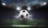 Fototapeta Sport -  Moving soccer ball around splash drops on the stadium field.