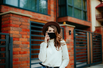 young woman with mobile phone in the city in mask. coronavirus. covid-19.  