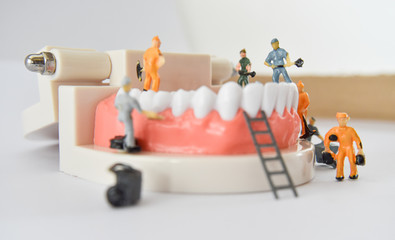 Wall Mural - miniature people to repair a tooth or small figure worker cleaning tooth model as medical and healthcare. Idea for cleaning dental care or dentist.