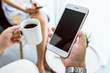© sitthiphong - Hand holding smartphone mockup of blank screen on the table. Take your screen to put on advertising.