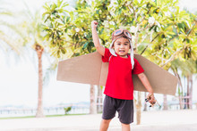 Happy Asian Funny Child Or Kid Little Boy Smile Wear Pilot Hat And Goggles Play Toy Cardboard Airplane Wing Flying Against Summer Sky Cloud On Trees Garden Background, Startup Freedom Concept