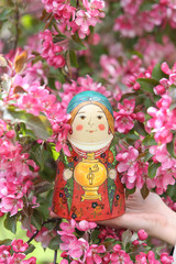 Wall Mural - Matryoshka. Nested doll. Russian traditional handicraft. Wooden nesting toy: vintage matryoshka. Pink flowers of blossoming spring apple-tree, grade 