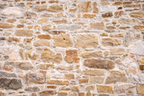 Fototapeta Desenie - Eine alte verwitterte Steinmauer mit kleinen und großen Steinen als Hintergrund
