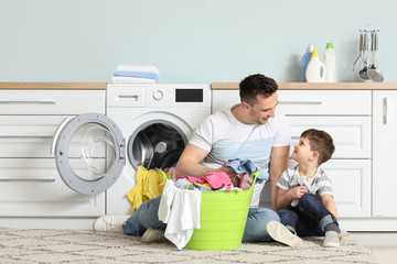 Wall Mural - Man and his little son doing laundry at home