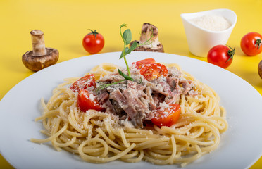 Spaghetti cooked pasta with ingredients on a yellow background. Colorful top and closeup view