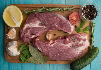 Raw juicy meat steaks ready for roasting on a wooden background