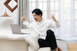 © Gengwit - Attractive asian male watch and cheer a sport event using laptop at home.