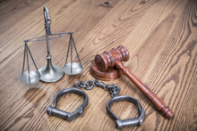Law Scales, Judge's Gavel And Vintage Antique Aged Handcuffs On Textured Oak Wooden Table Background. Symbols Of Justice Conceptual Still Life. Retro Old Style Filtered Photo