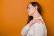 Tired unhappy young woman massaging hurt stiff neck isolated on brown studio background, fatigued sad girl rubbing tensed muscles to relieve joint shoulder pain, fibromyalgia concept. Selective focus