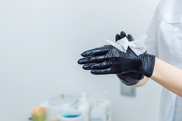 How to do waxing. Womens DIY. Step 2 of 8 Disinfect your hands. On the hands of dressed black gloves. Gloves are wiped with a black cloth.