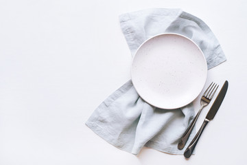 An empty plate and Cutlery on a white table. Top view. Copy space for text.