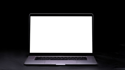 Computer with blank screen on the table on a black background. Mockup and space for text and advertising. Copy space