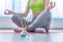 Fitness Woman In Lotus Pose With Aroma Sticks And Essential Oil Bottle During Yoga Training, Aromatherapy Treatments And Meditation. Mental Health
