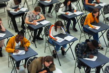 Focused High School Students Taking Exam At Desks In Classroom