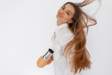 Beautiful teenage girl blowing her hair with hairdryer. Beauty and hait concept.