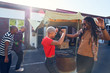 © Trevor Adeline/Caia Image - Smiling friends dancing and barbecuing in parking lot