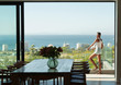 © Paul Bradbury/Caia Image - Young woman standing on modern balcony with sunny ocean view