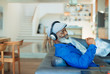 © Paul Bradbury/Caia Image - Happy man with headphones listening to music on living room sofa