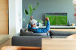 © Paul Bradbury/Caia Image - Excited man cheering, watching soccer match on TV in living room