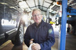 © Tom Merton/Caia Image - Portrait confident male mechanic wiping hands in auto repair shop