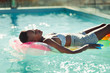 © Paul Bradbury/Caia Image - Serene young woman laying on inflatable raft in sunny swimming pool