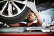 © Tom Merton/Caia Image - Male mechanic working under car, examining tire in auto repair shop