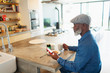 © Paul Bradbury/Caia Image - Man enjoying breakfast and using smart phone in morning kitchen