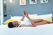 © Paul Bradbury/Caia Image - Young woman relaxing on bed, listening to music with mp3 player and headphones