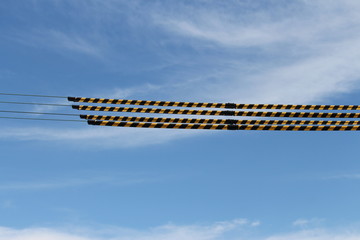 Yellow and black striped synthetic tubes that (Tiger tails) They are clipped together over powerlines to provide a useful visual indication of live overhead powerlines. Blue sky