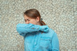 a young girl in a blue shirt and protective gloves closed her eyes and sneezed into her elbow.