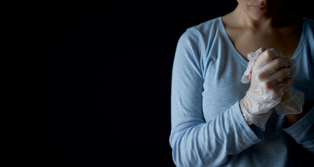 Wall Mural - Woman prays with faith to GOD. Religion care during the pandemic crisis. Hands in disposable gloves are folded in prayer. Online church worship.